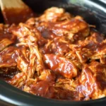 Overhead view of BBQ chicken in a slow cooker with barbecue sauce