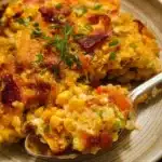 Delicious Loaded Corn Casserole topped with cheese and herbs, served in a baking dish.